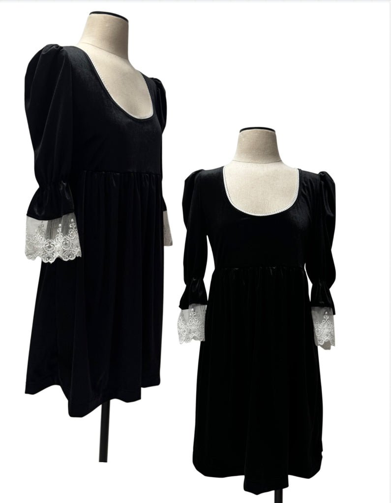 A black velvet dress with puffed sleeves and white lace cuffs
