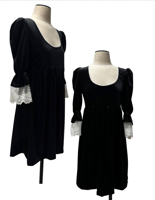A black velvet dress with puffed sleeves and white lace cuffs