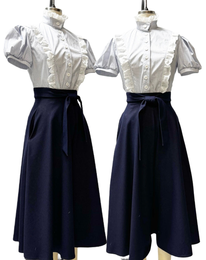 Two mannequins wearing white tops with short sleeves and navy blue skirts on a white background.