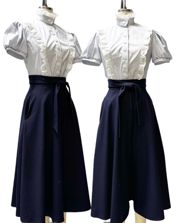 Two mannequins wearing white tops with short sleeves and navy blue skirts on a white background.