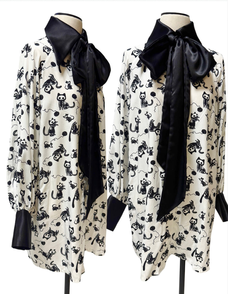 
white blouse with black cat pattern and a black bow tie.