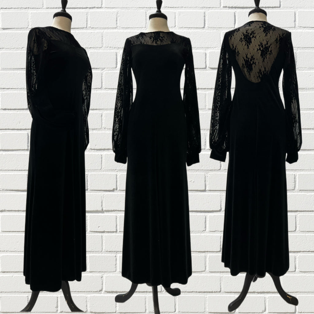 Mannequin forms in front of a white brick wall showing the Lola Maxi Dress in velvet has an A-line body paired with a sheer black lace neckline and gathered bishop sleeves. 