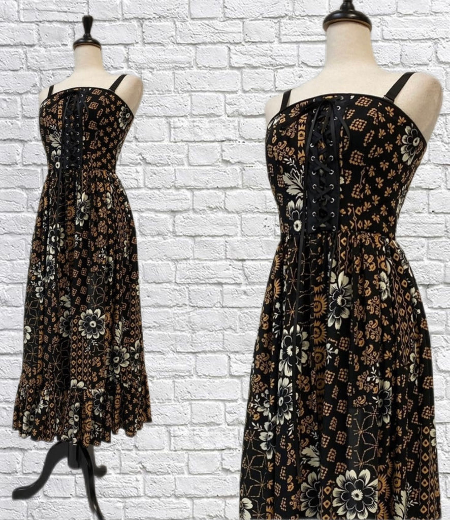 Mannequin forms showing the Louise in this gorgeous boho printed rayon with fitted bodice, lace up front detail, detachable bra straps, gathered skirt with ruffle hem in front of a white brick backdrop.