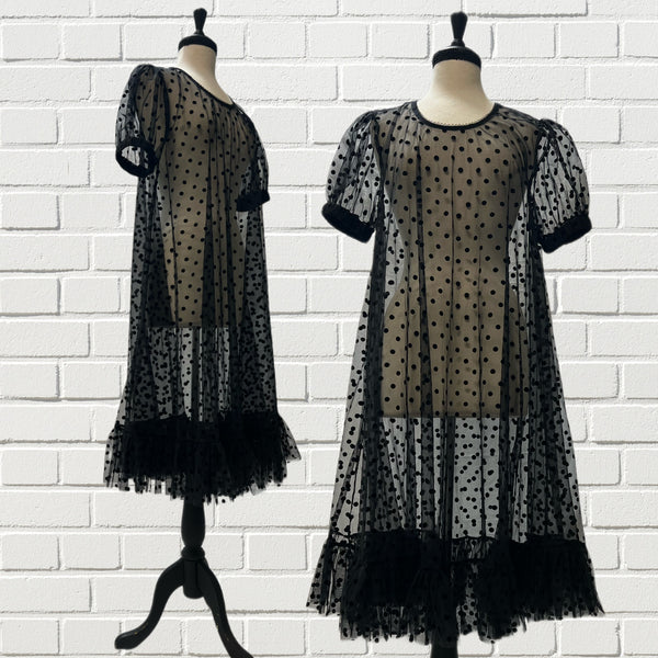 Mannequin forms showing the Sheer Molly Dress in Swiss Dot has an oversized fit, short puffed sleeves, and full circle body in front of a white brick backdrop.