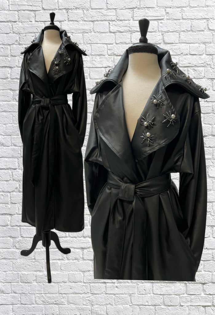 Mannequin form showing the Faux leather overcoat with wide lapels, tie sash, and side seam pockets. Studded with silver pearl spider pins. 