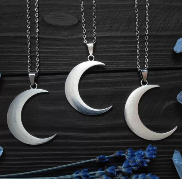 Silver crescent moon necklaces displayed against a dark wood grain.