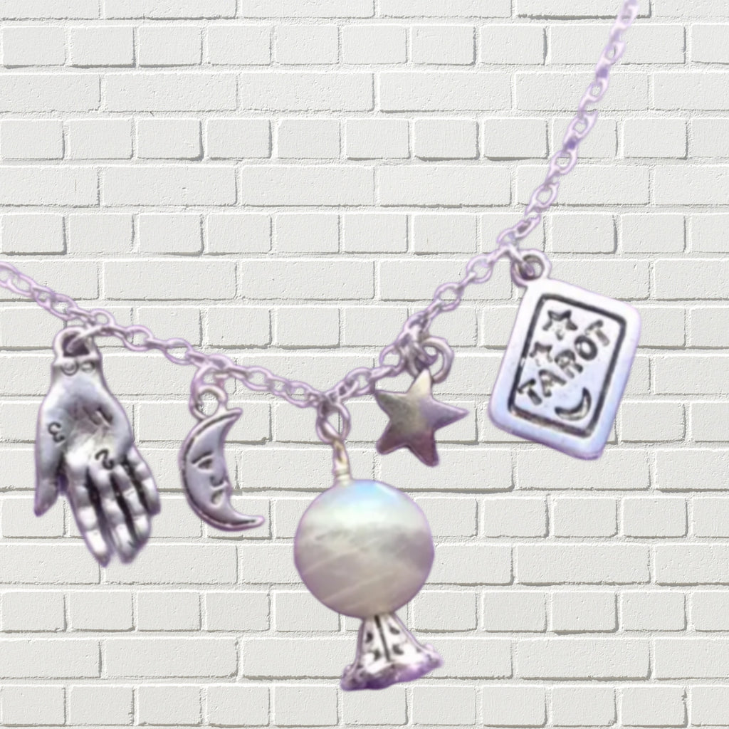 Silver necklace featuring charms depicting palm reading hand, crescent moon, crystal ball, star, and a tarot card.