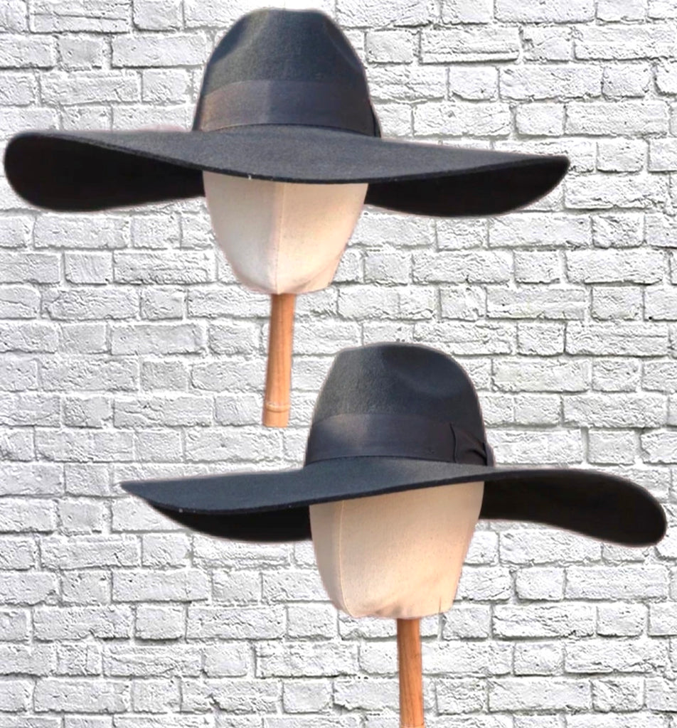 Mannequin heads showing an oversized fedora in black felt wool against a white brick backdrop.