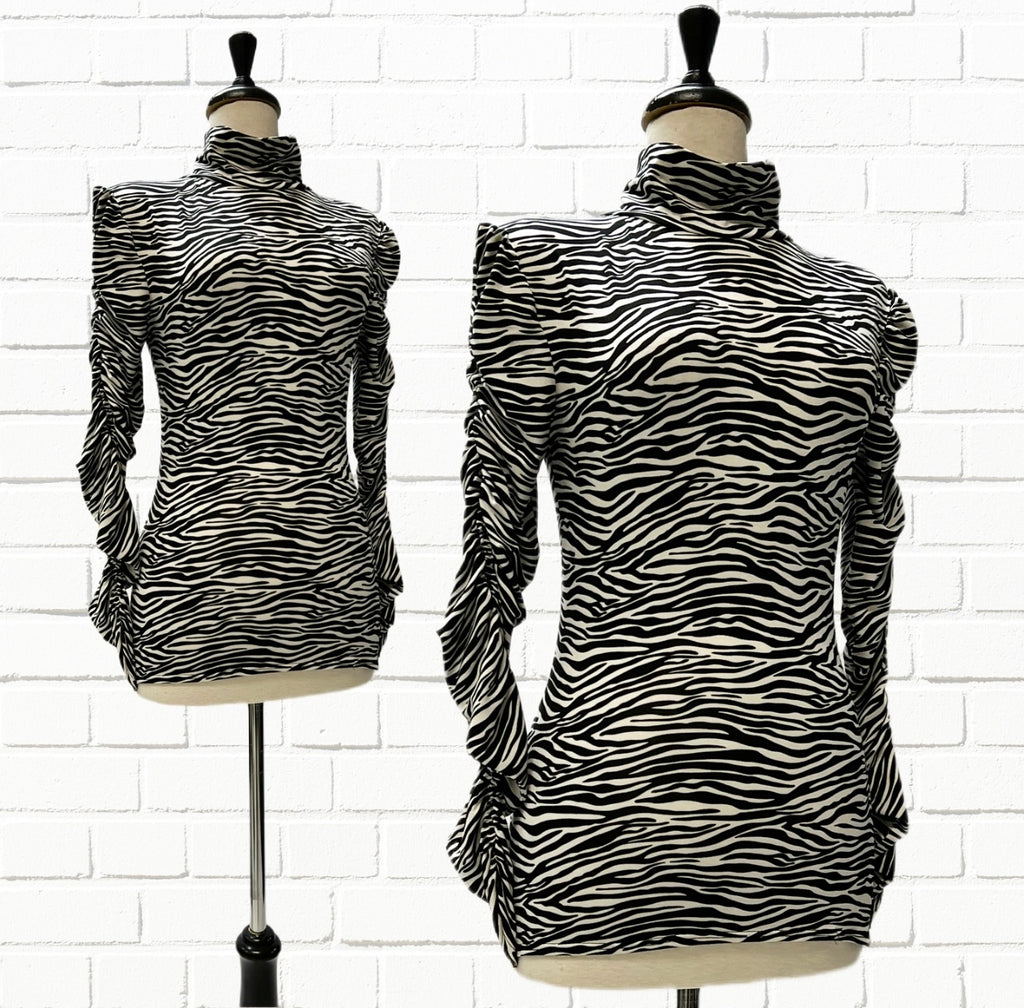 Mannequin bust in front of a white brick background showing the Ruby Top in soft bamboo knit zebra stripes in black & white. 