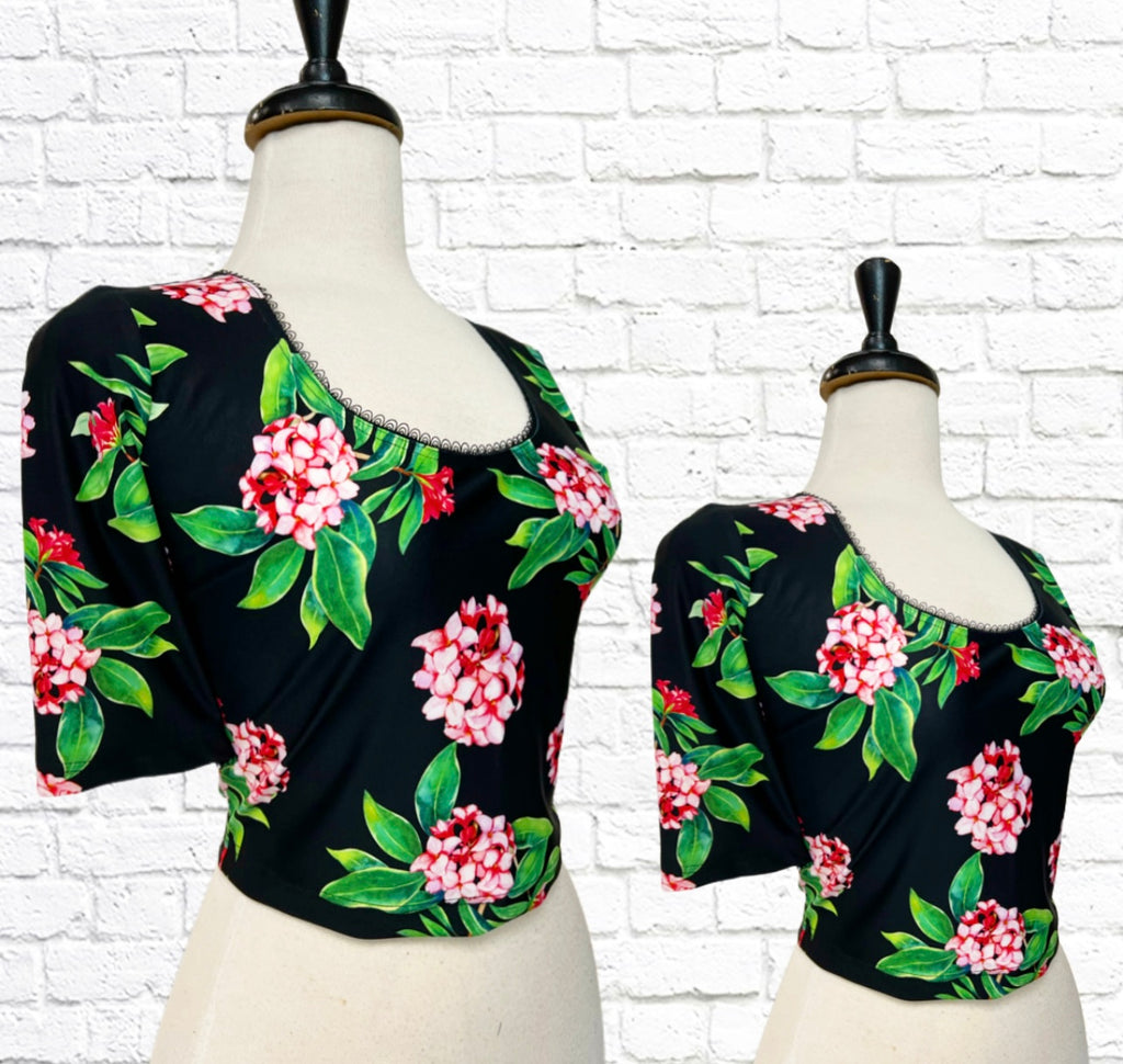 Mannequin bust with the Serena Top in a Tropical Garden print with pink blossoms against a black background.