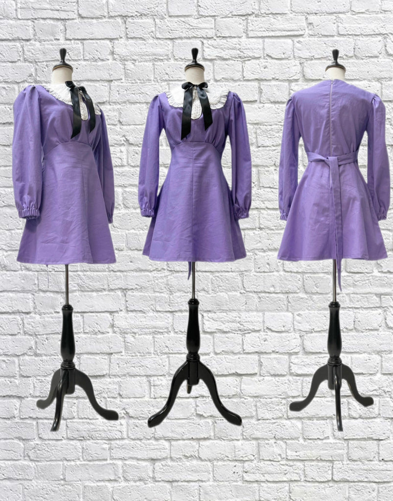 Mannequin forms showing the side, front, and back profile of the Vera Dress in Lavender Linen. Empire waist, long sleeves gathered at the wrist, tie back, eyelet collar with ruffle trim, and a black satin neck bow.