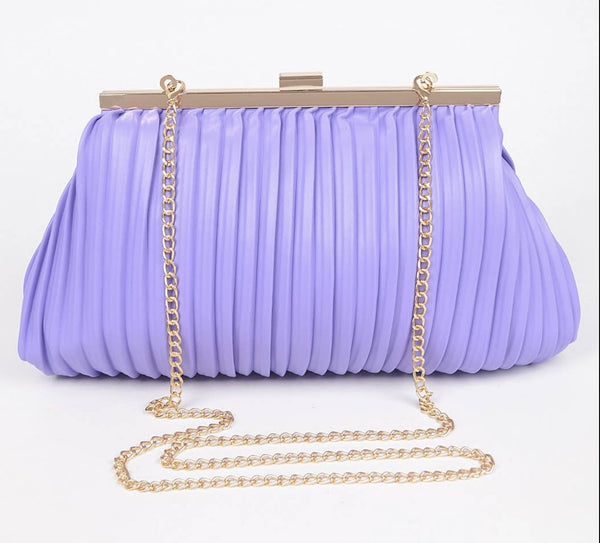 A lavender handbag with pleated material and a gold crossbody chain sits against a white backdrop.