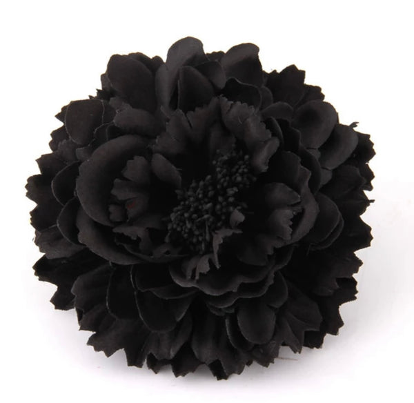 A black floral clip that can be worn as a hair clip or brooch sits against a white background.